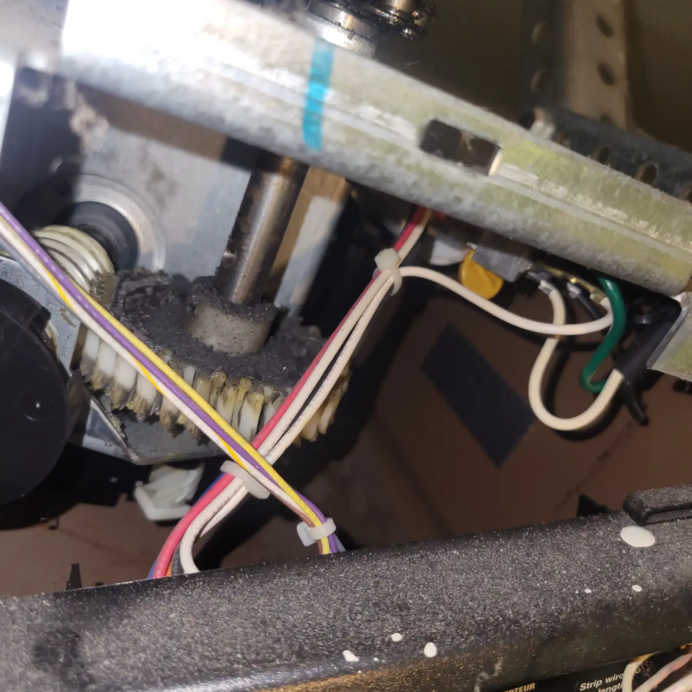 Inside a garage door opener showing gear, wiring, and drive shaft